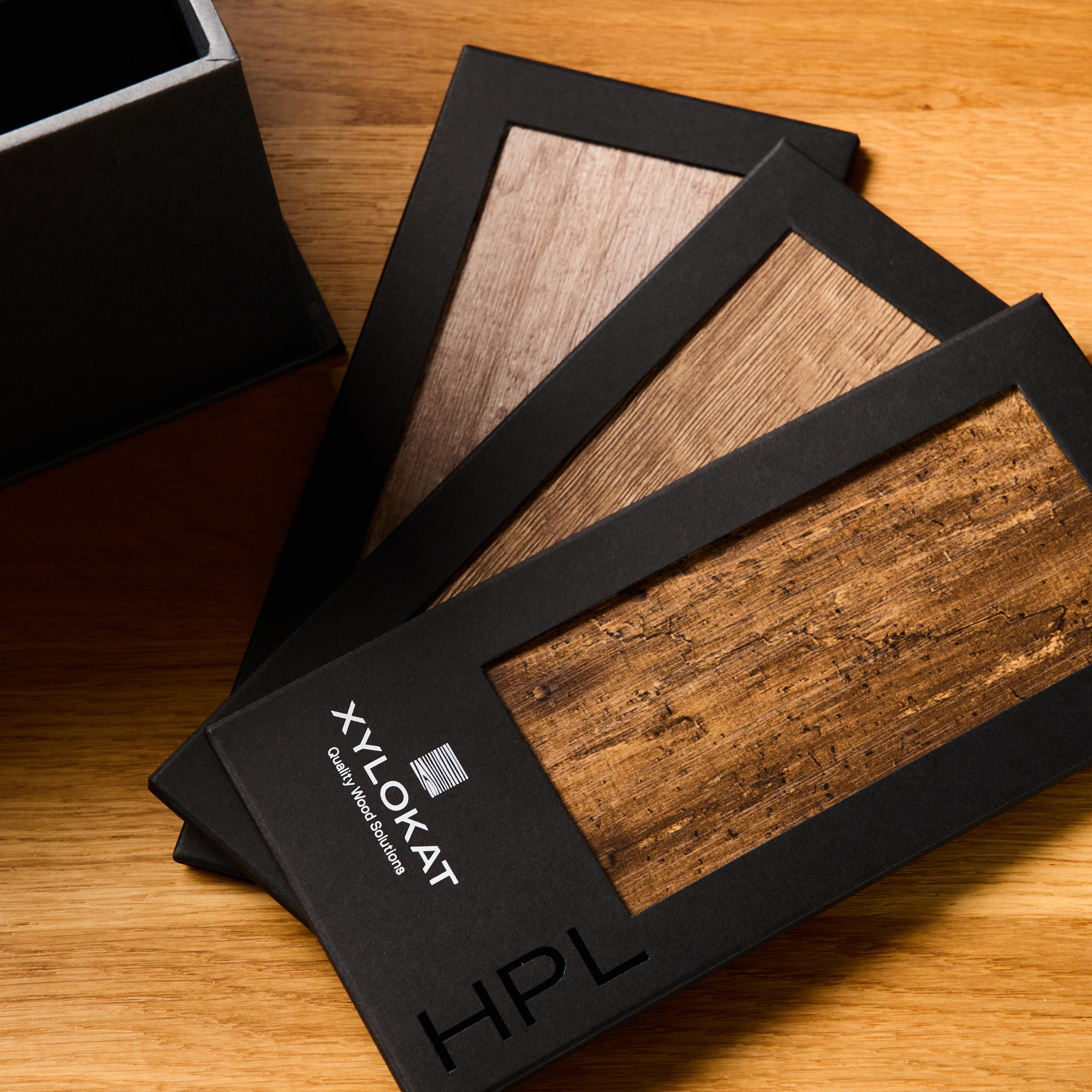 Τα HPL Laminated Panels της XYLOKAT παρουσιάζονται σε σχήμα βεντάλιας. Κάθε δείγμα έχει μαύρο περίγραμμα και αναδεικνύει ξύλινες υφές και ανθεκτική επιφάνεια.